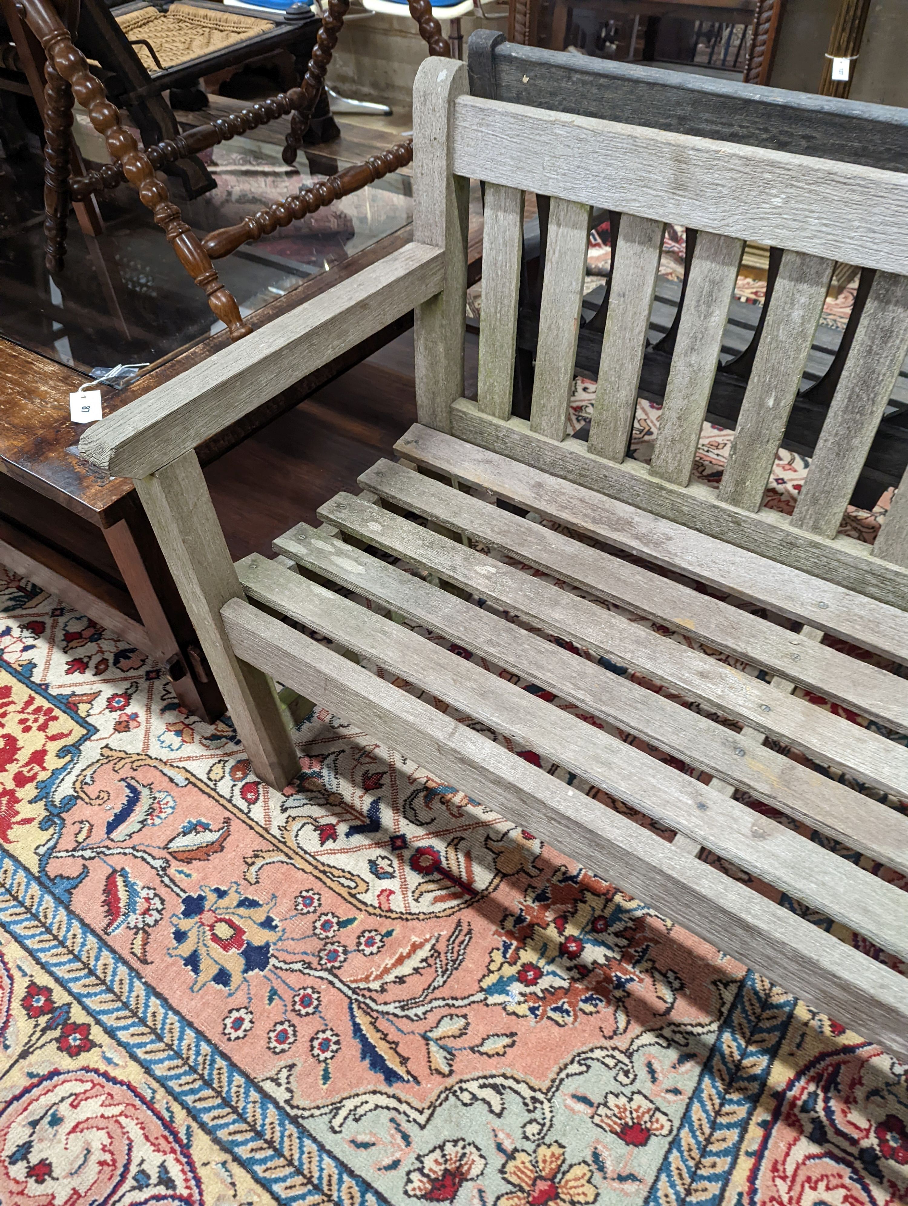 A weathered teak slatted garden bench